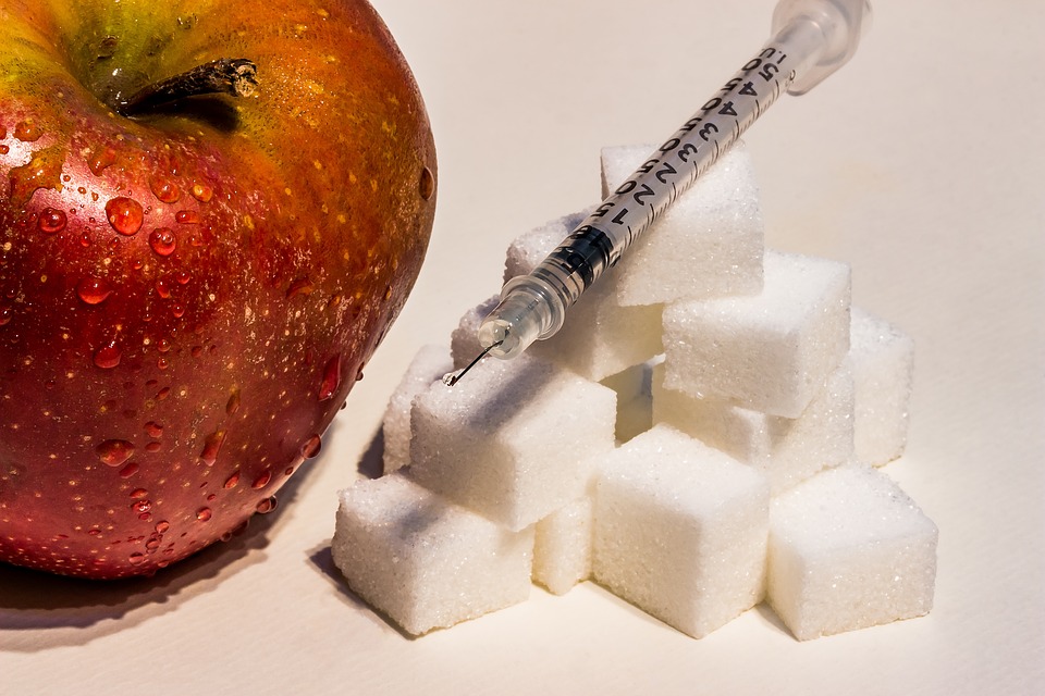 Red Apple Beside Cubes Of Sugar. There Is A Clear Syringe On Top Of The Cubes Of Sugar.
