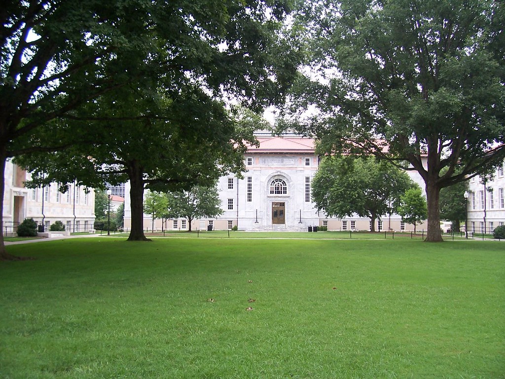 Image Of A Building Set Behind Some Large Trees And An Expanse Of Green Grass In Front. This Is An Image Of A Building At Emory University.