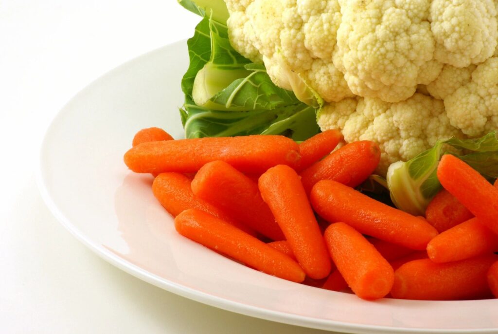 Close up image of carrots and cauliflower on a white place against a white background. 