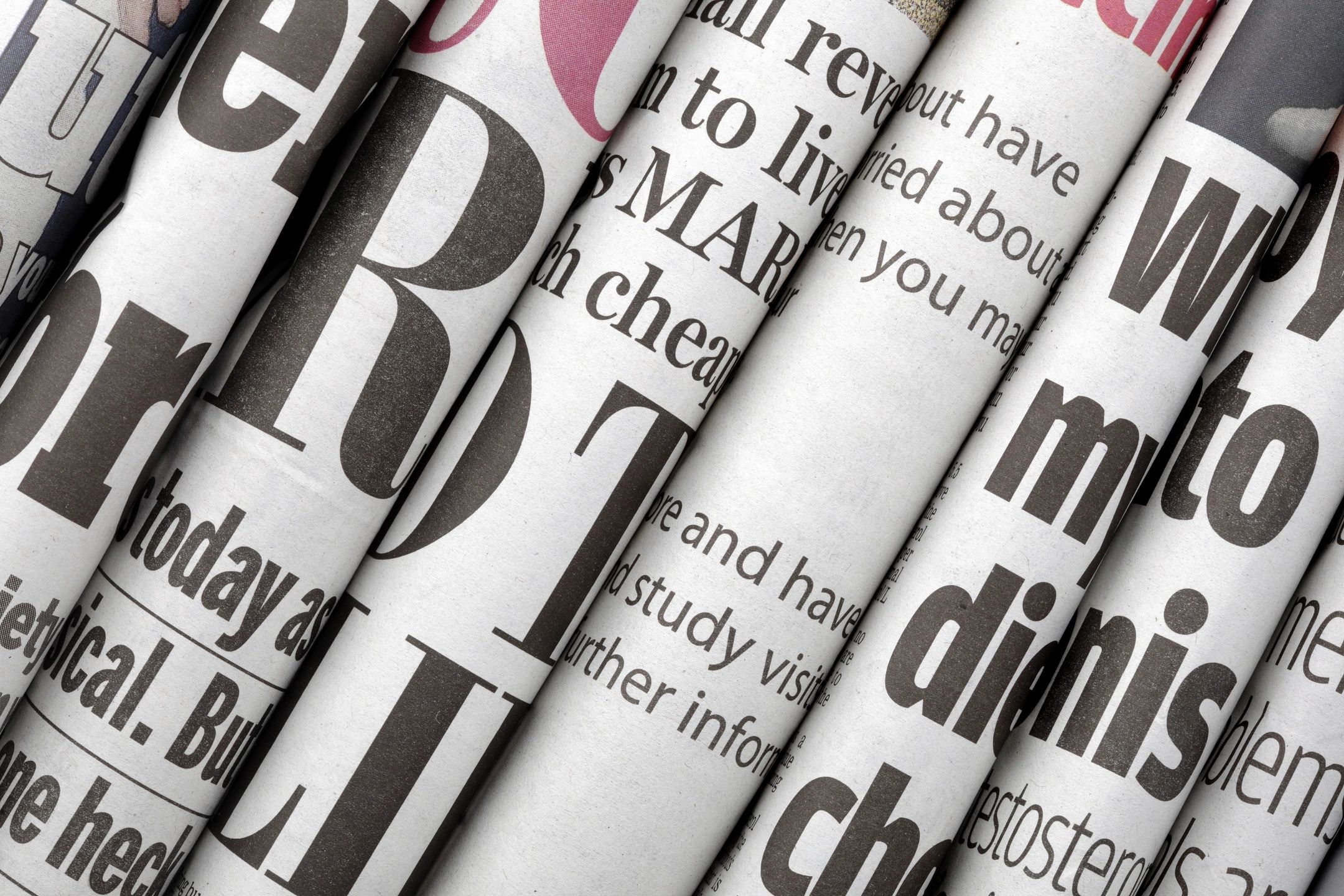 Image Of Several Newspapers All Folded And Placed Next To Each Other Such That You Can Only See The Fold.