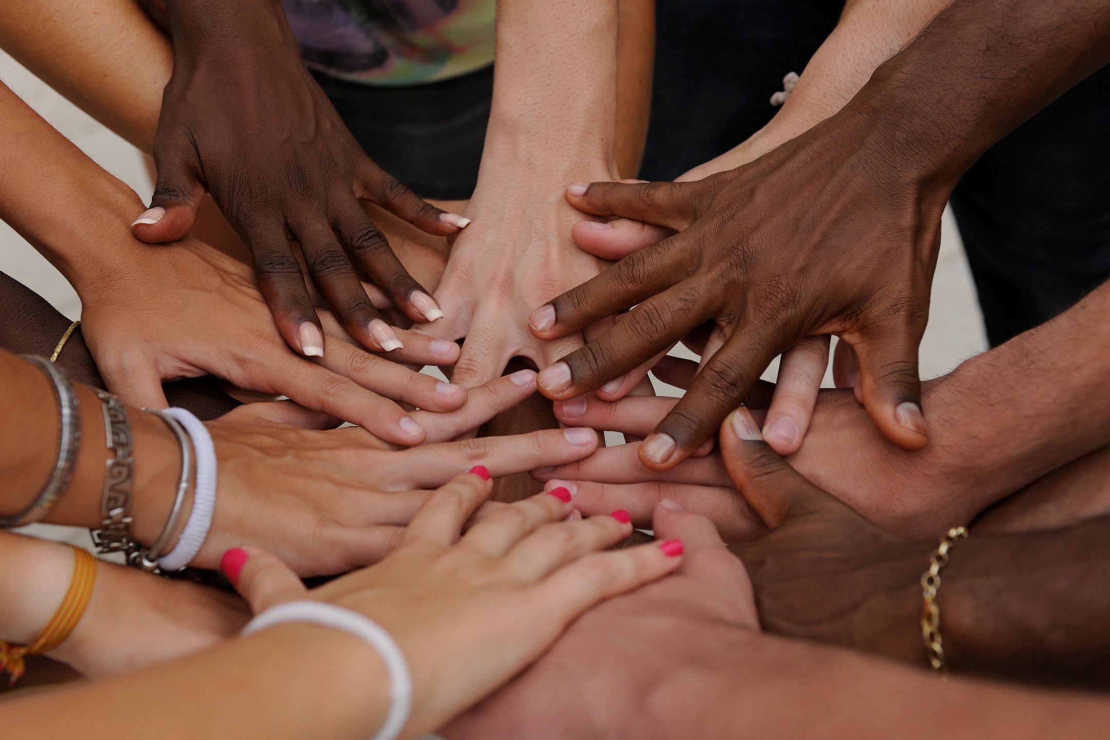 Image Of Several Women's Hands Of Different Races All Touching In The Middle.